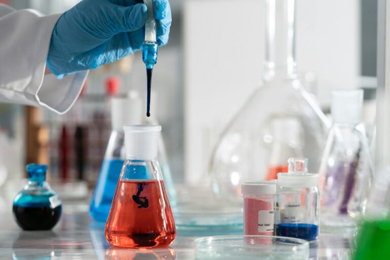 Scientist conducting a laboratory experiment with colorful chemical solutions and scientific glassware.